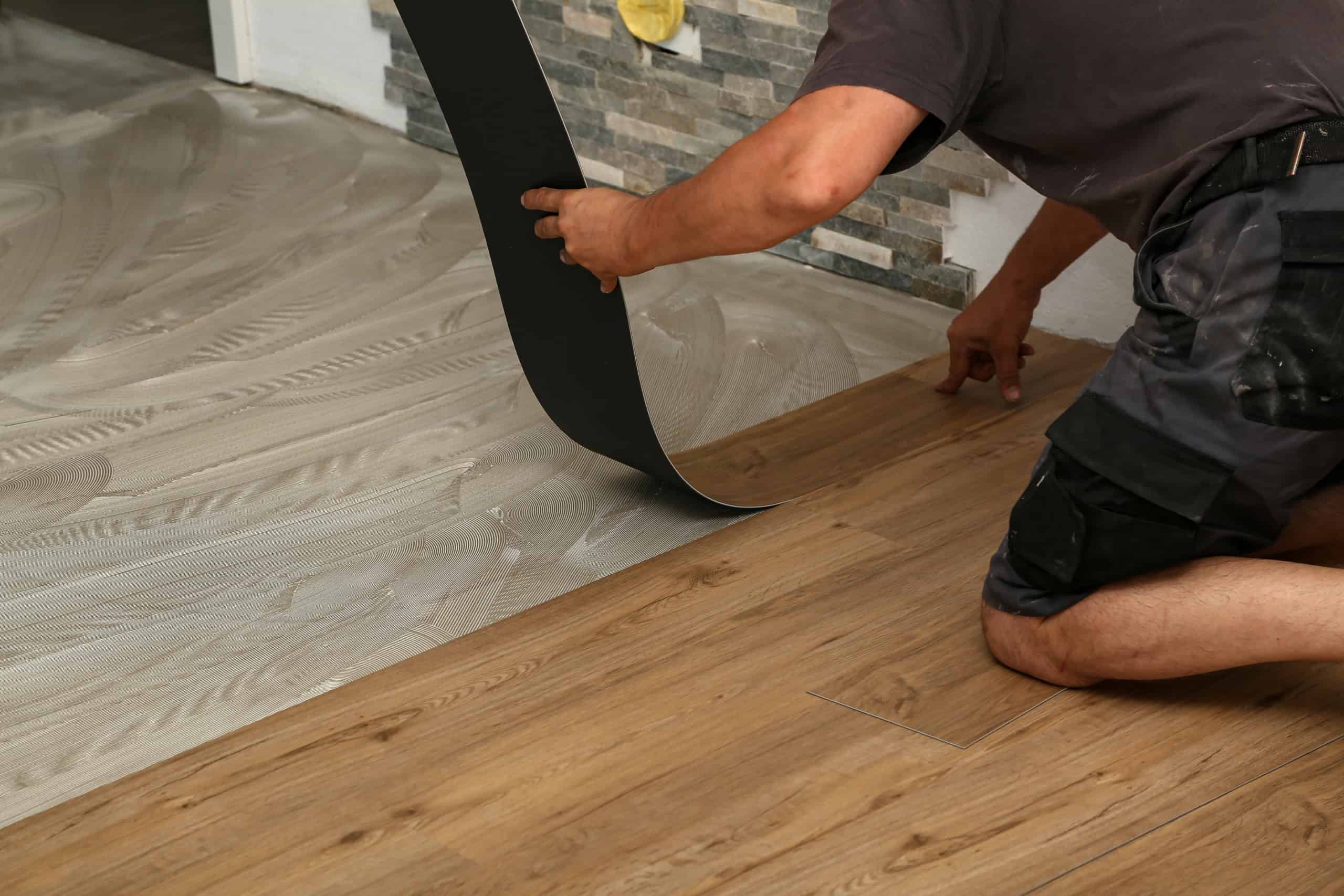 Low angle shot of a worker installing a new set of vinyl tiles on the floor